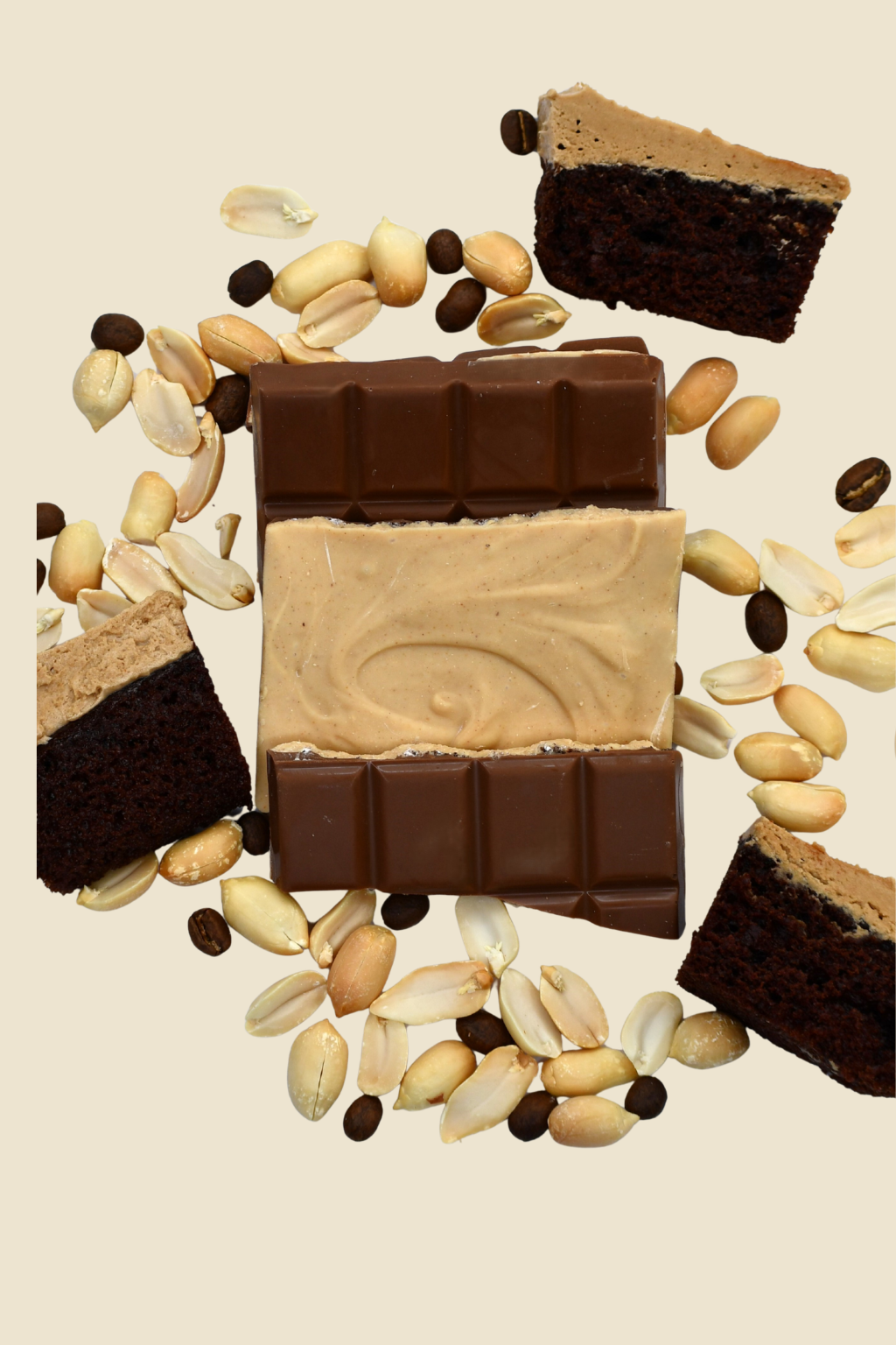 Broken chocolate and peanut butter bar surrounded by peanuts, cake piecs and coffee beans on a beige background