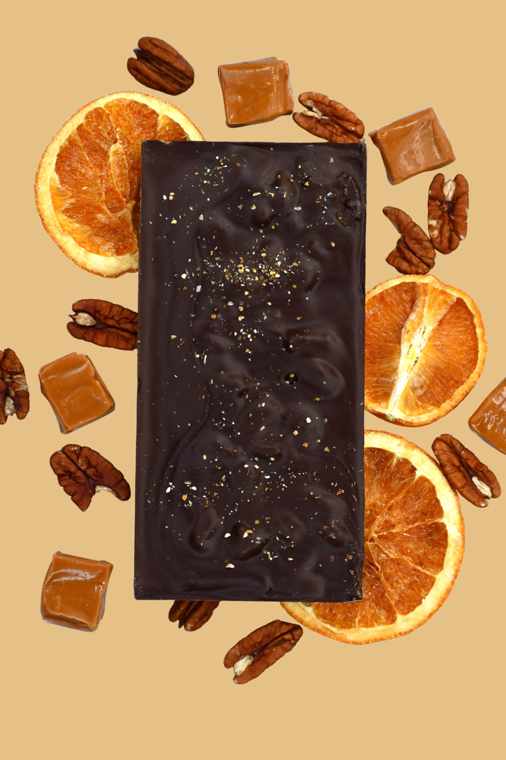Dark chocolate bar with pecans and orange slices on a beige background